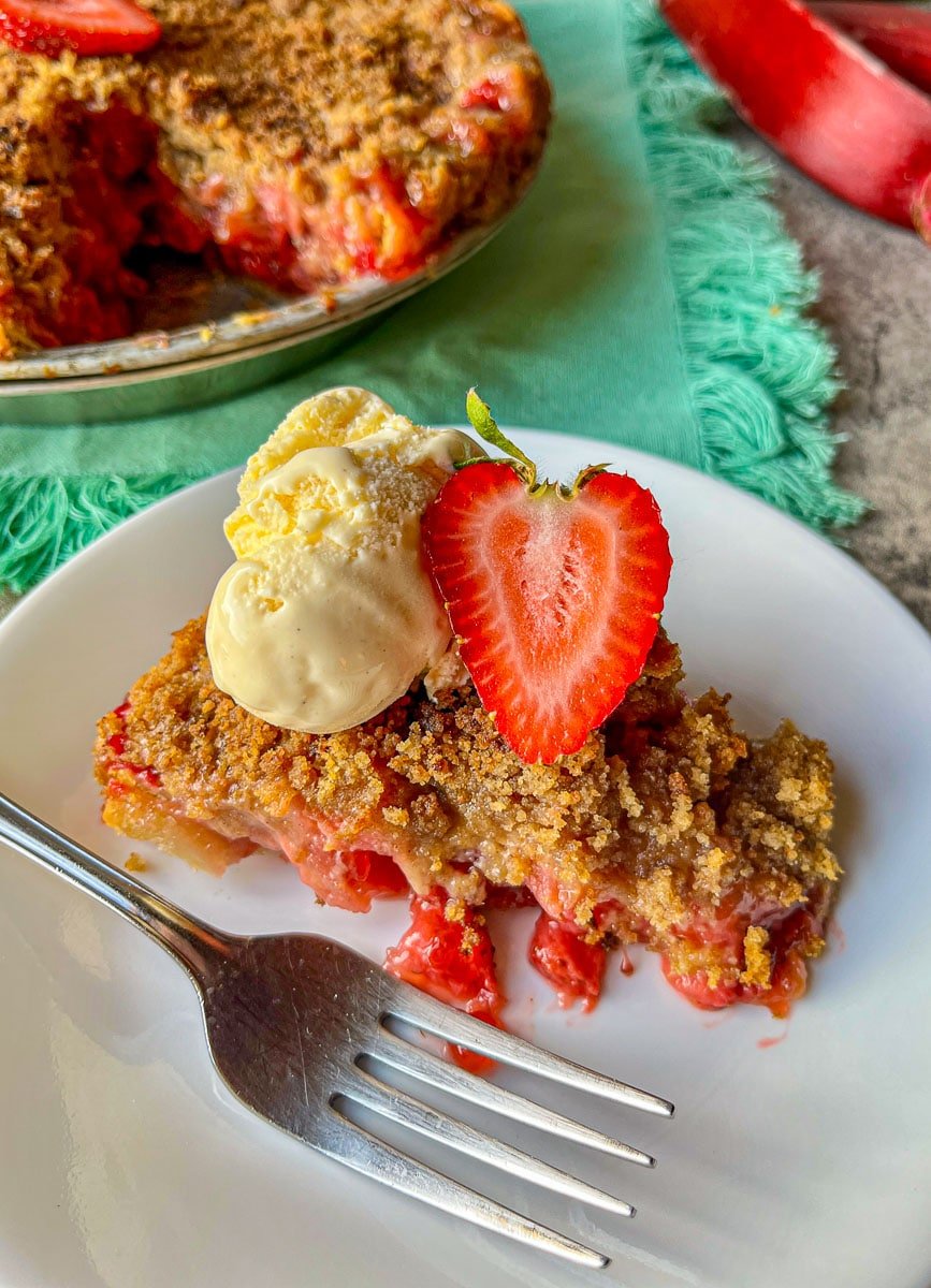a slice of old fashioned rhubarb pie with ice cream and a whole pie behind it