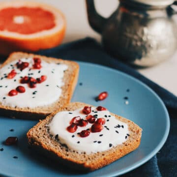 nigella seeds sprinkled on toast with cream cheese spread and pomegranate seeds
