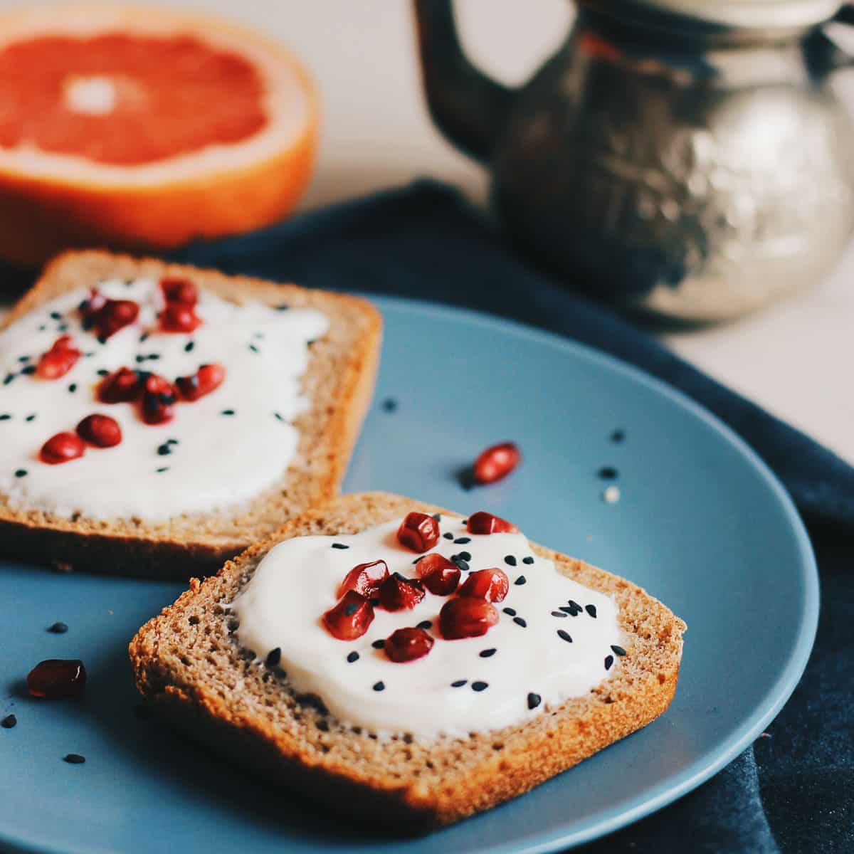 nigella seeds sprinkled on toast with cream cheese spread and pomegranate seeds