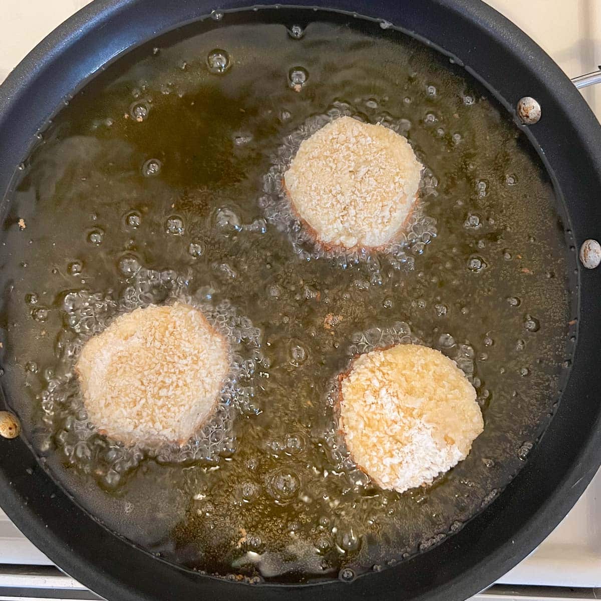 potato cheese balls being deep fried in a pan
