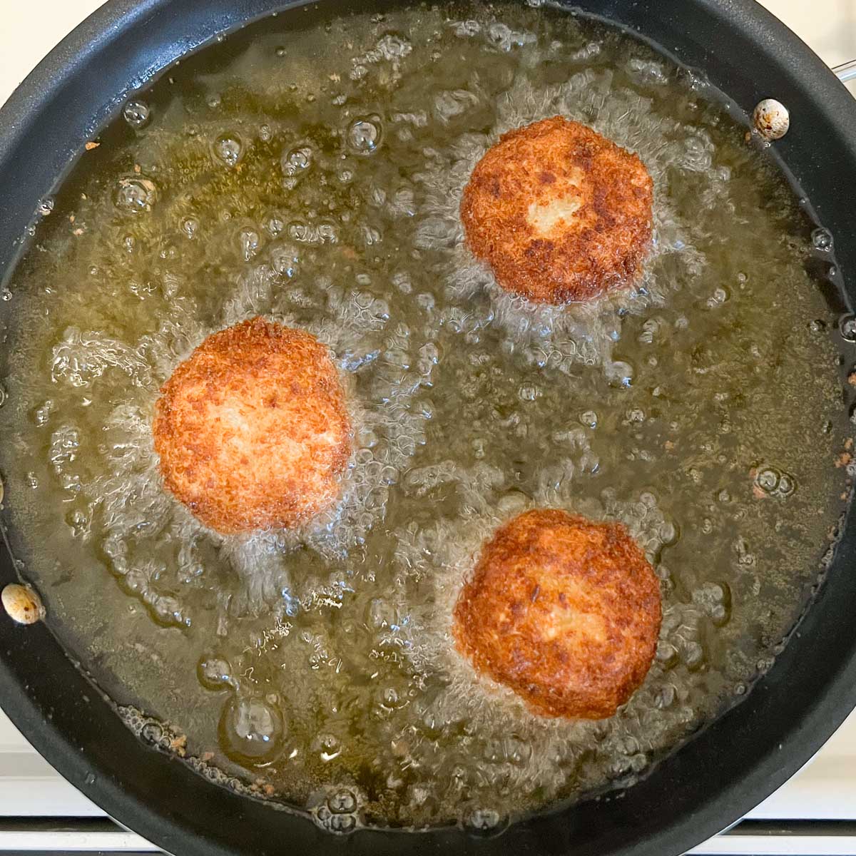 potato balls being deep fried after being rotated