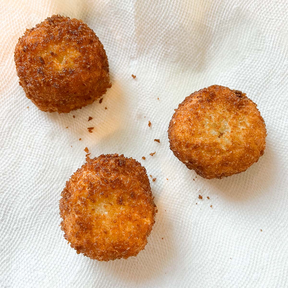 potato cheese balls draining excess oil on paper towel