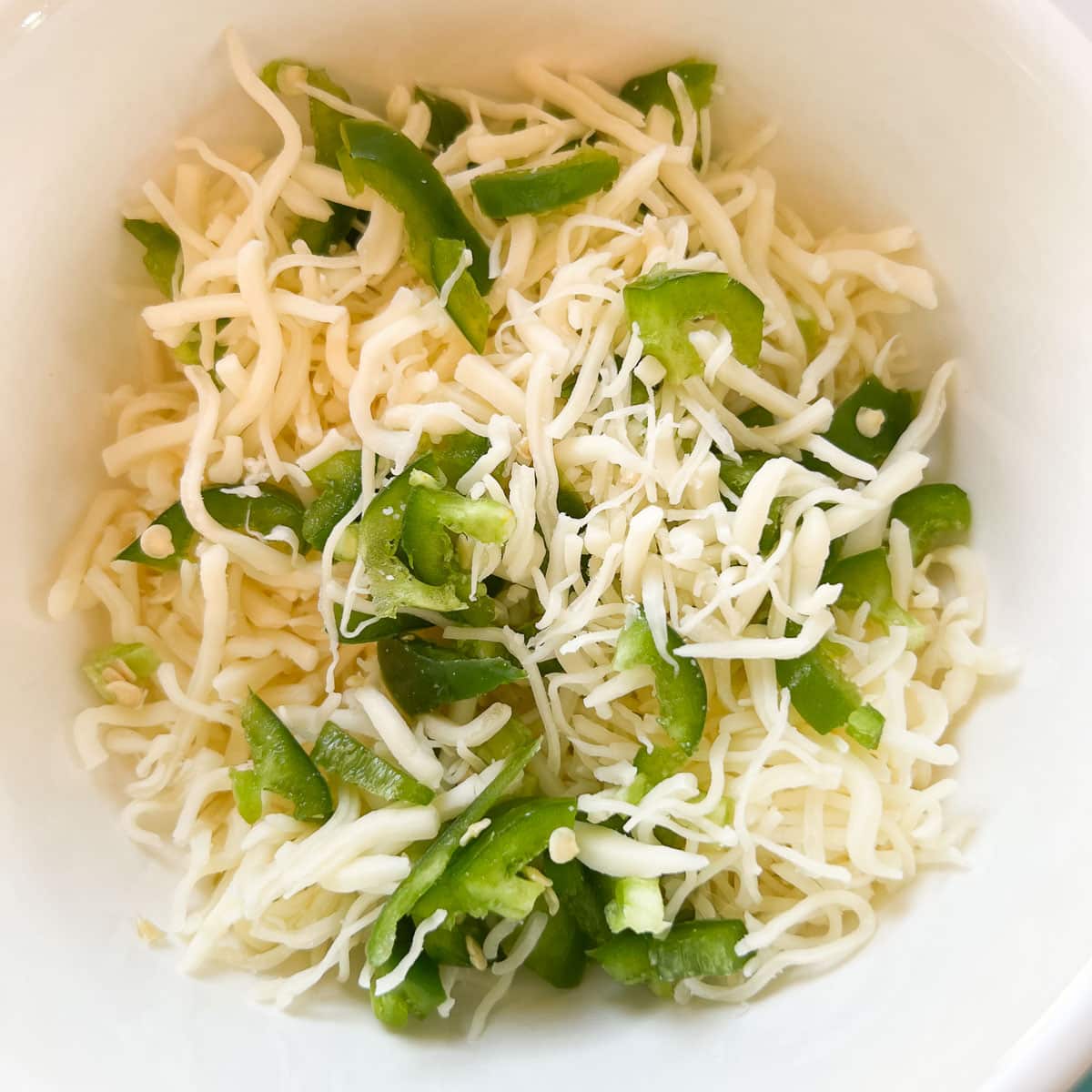 shredded cheese and diced jalapeños in a bowl