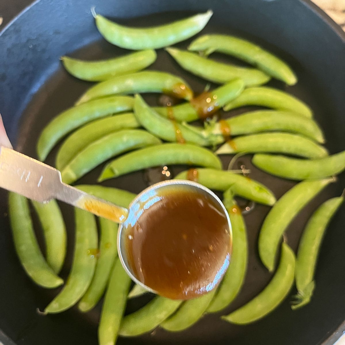 sauce being added to beans in a pan