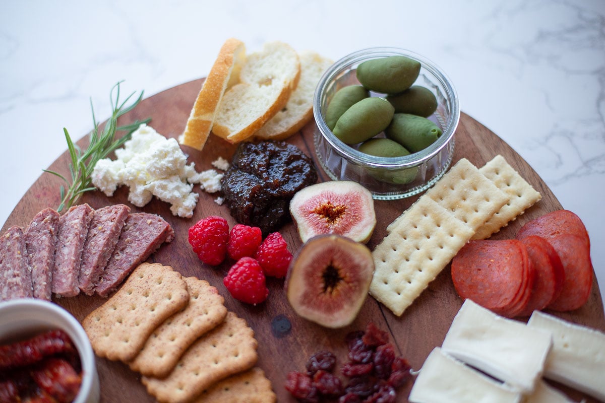 close up of a simple charcuterie board topped with cheese and various items