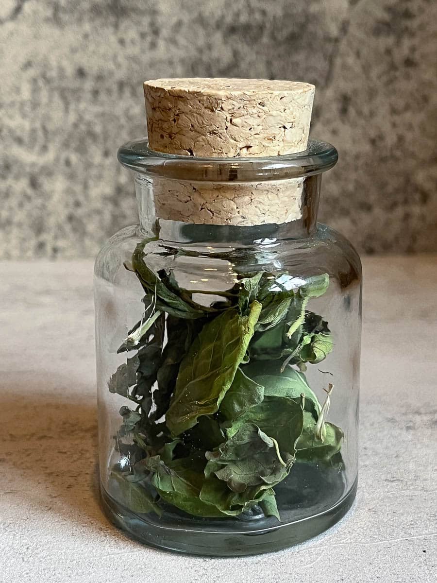 dried basil leaves in a glass jar