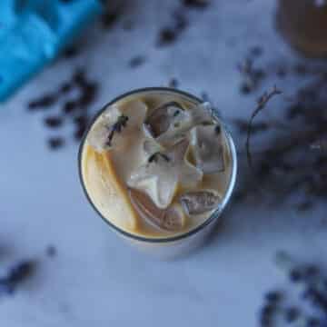 iced latte in a glass with coffee beans and lavender around it