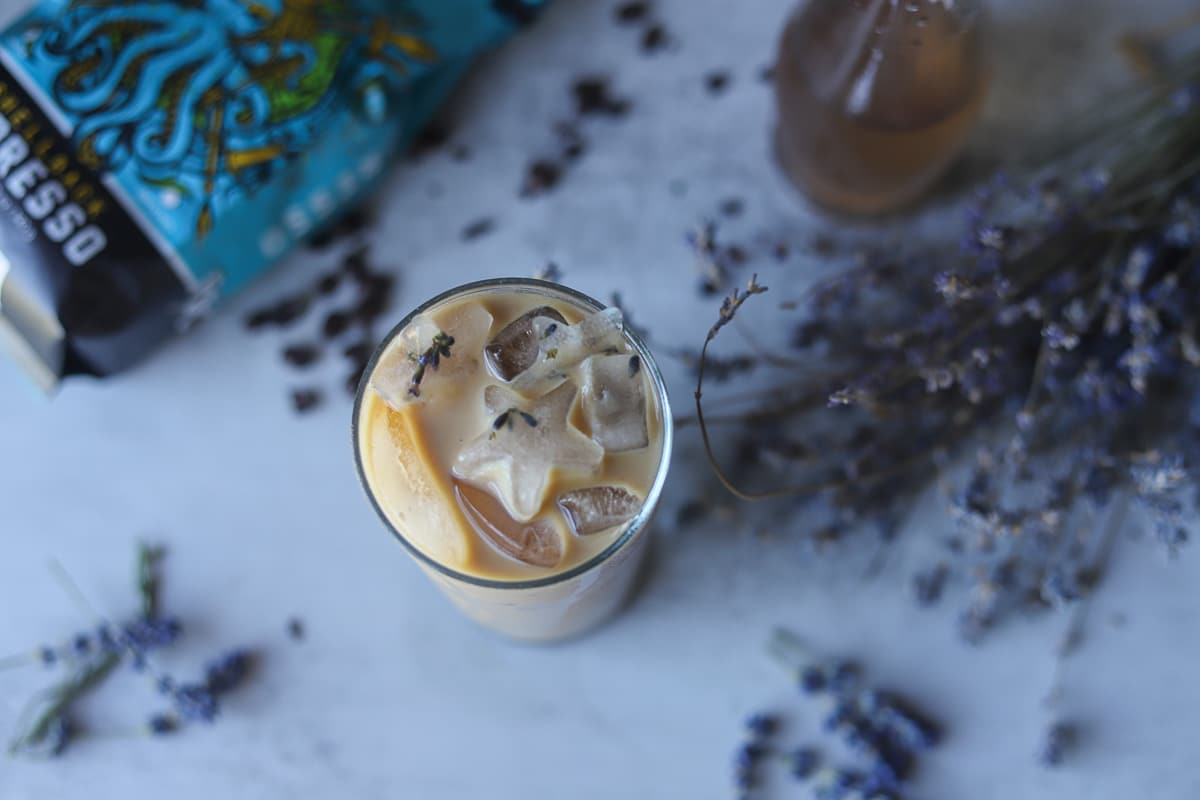 iced latte with lavender and coffee around it