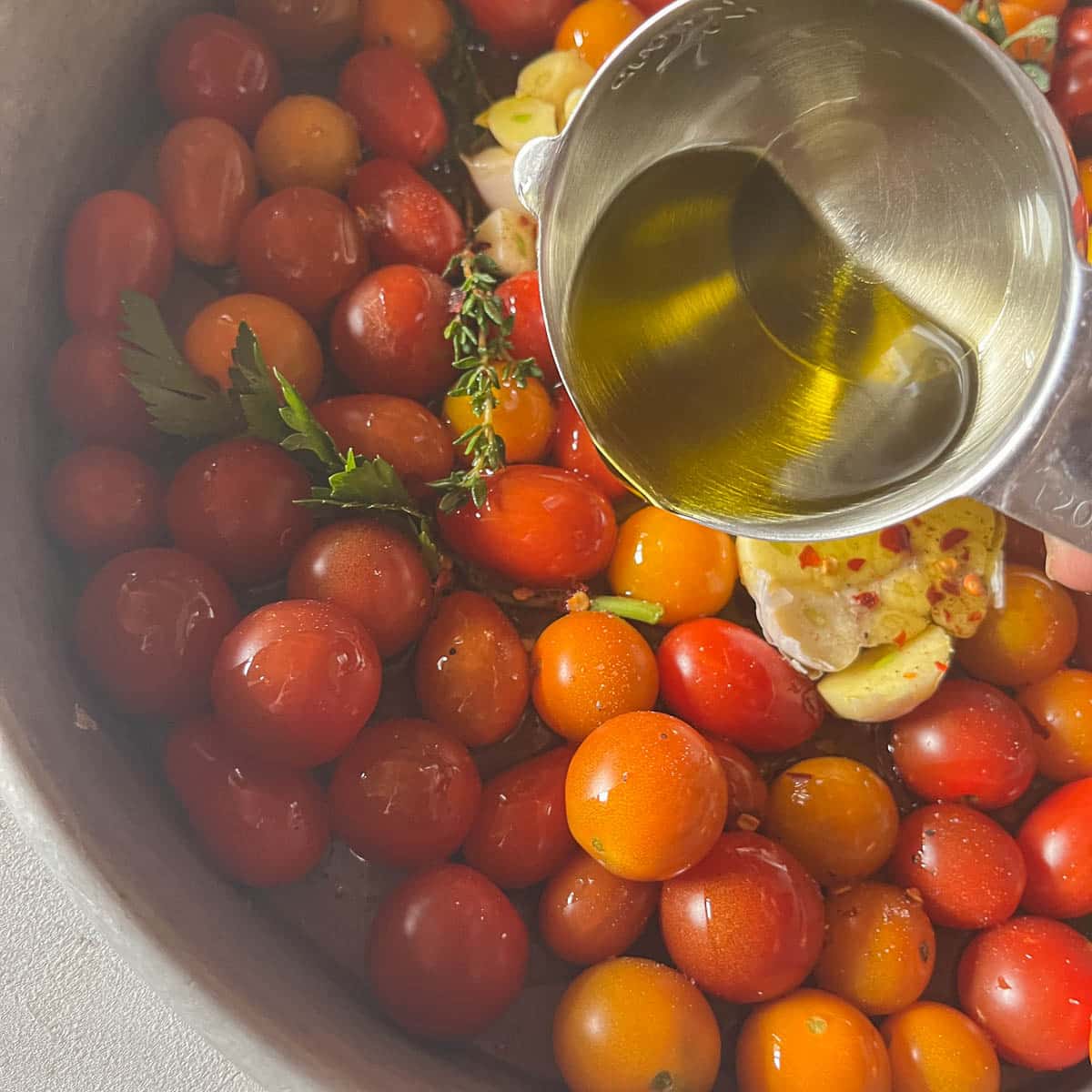 pouring olive oil over tomatoes in a pan