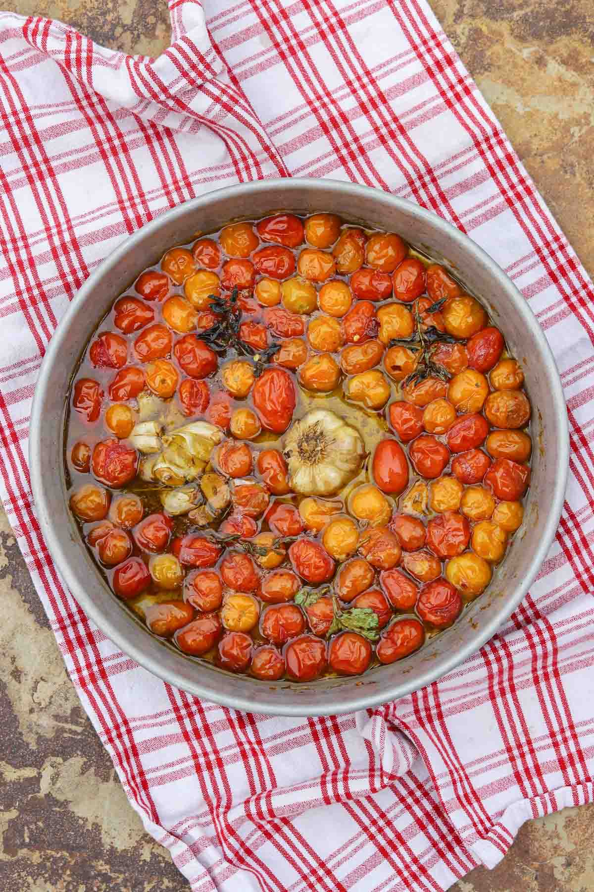 confit tomatoes in a round pan over a checkered washcloth