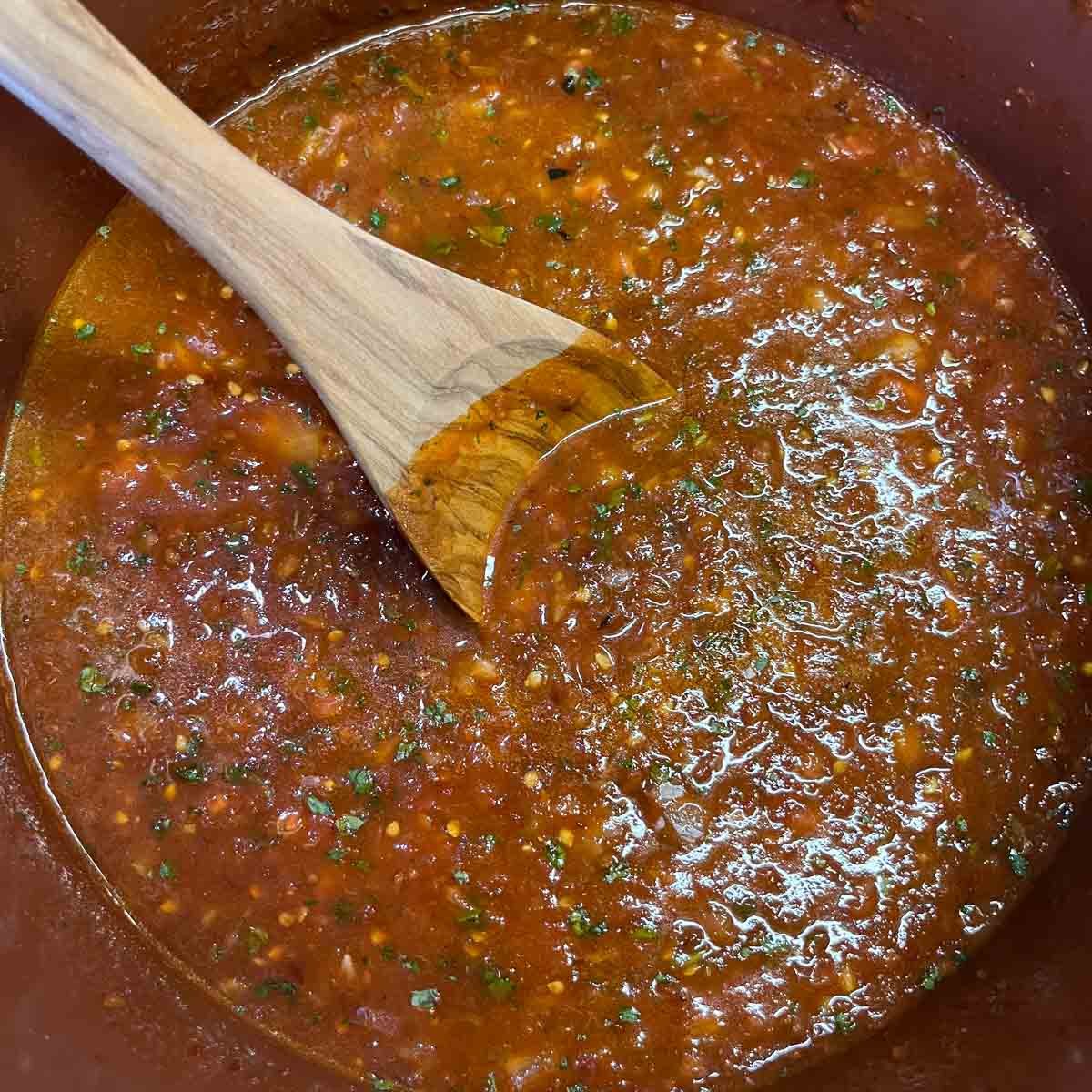 salsa being stirred with a wooden spoon