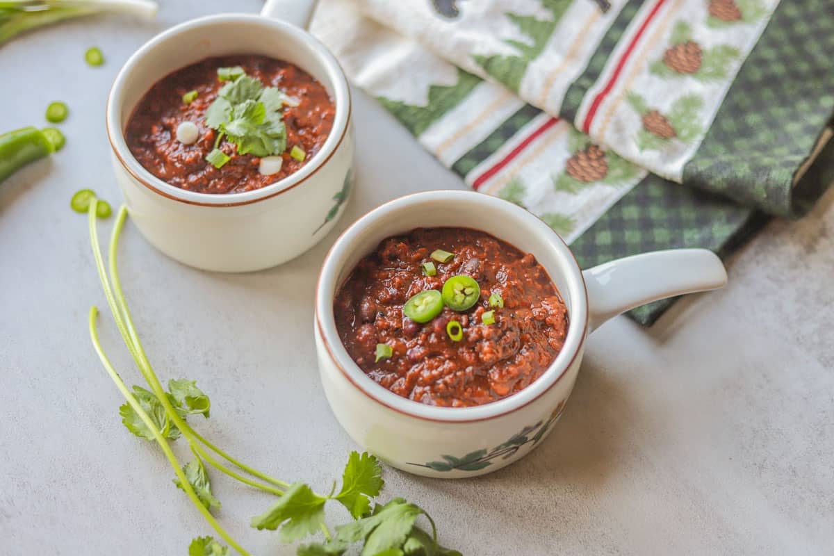 two bowls of chili topped with cilantro and green onion