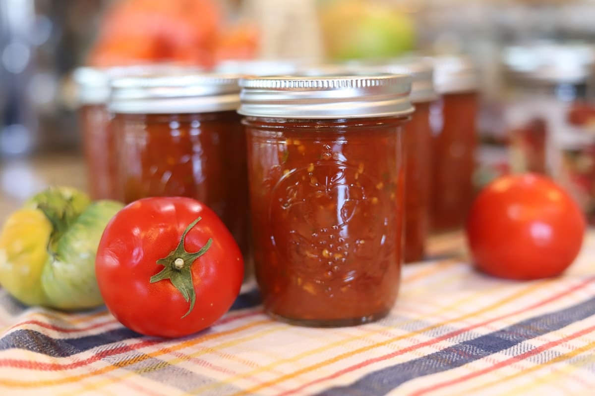 canned salsa with tomatoes in front of it