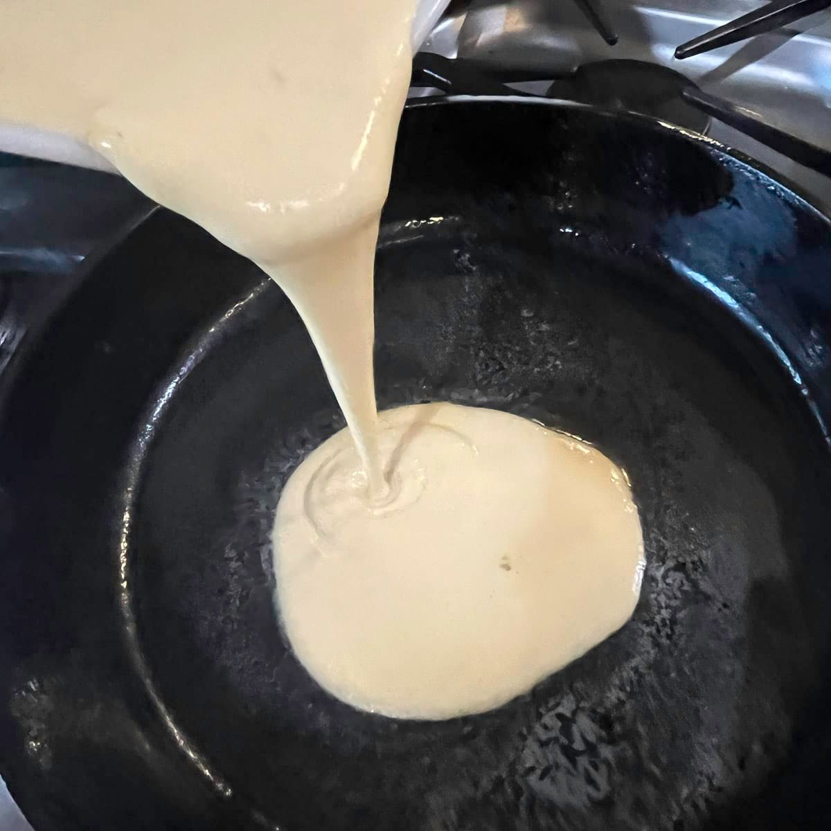pouring batter in a cast-iron skillet