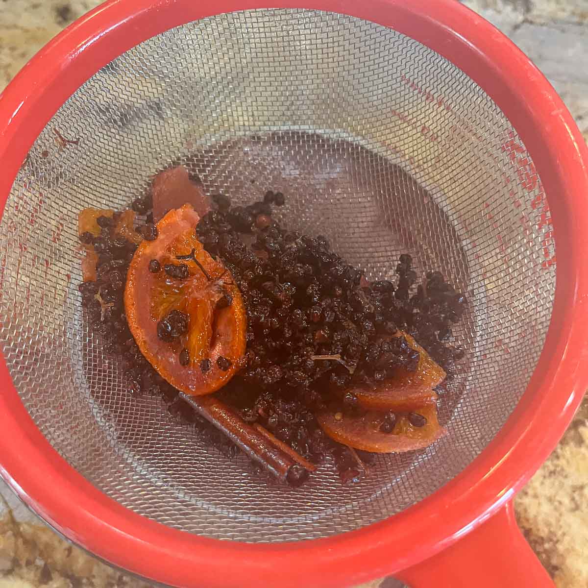 elderberries and spices in a strainer