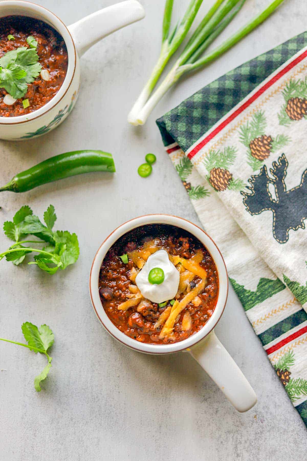 elk chili in two serving bowls with diced chiles and scallions