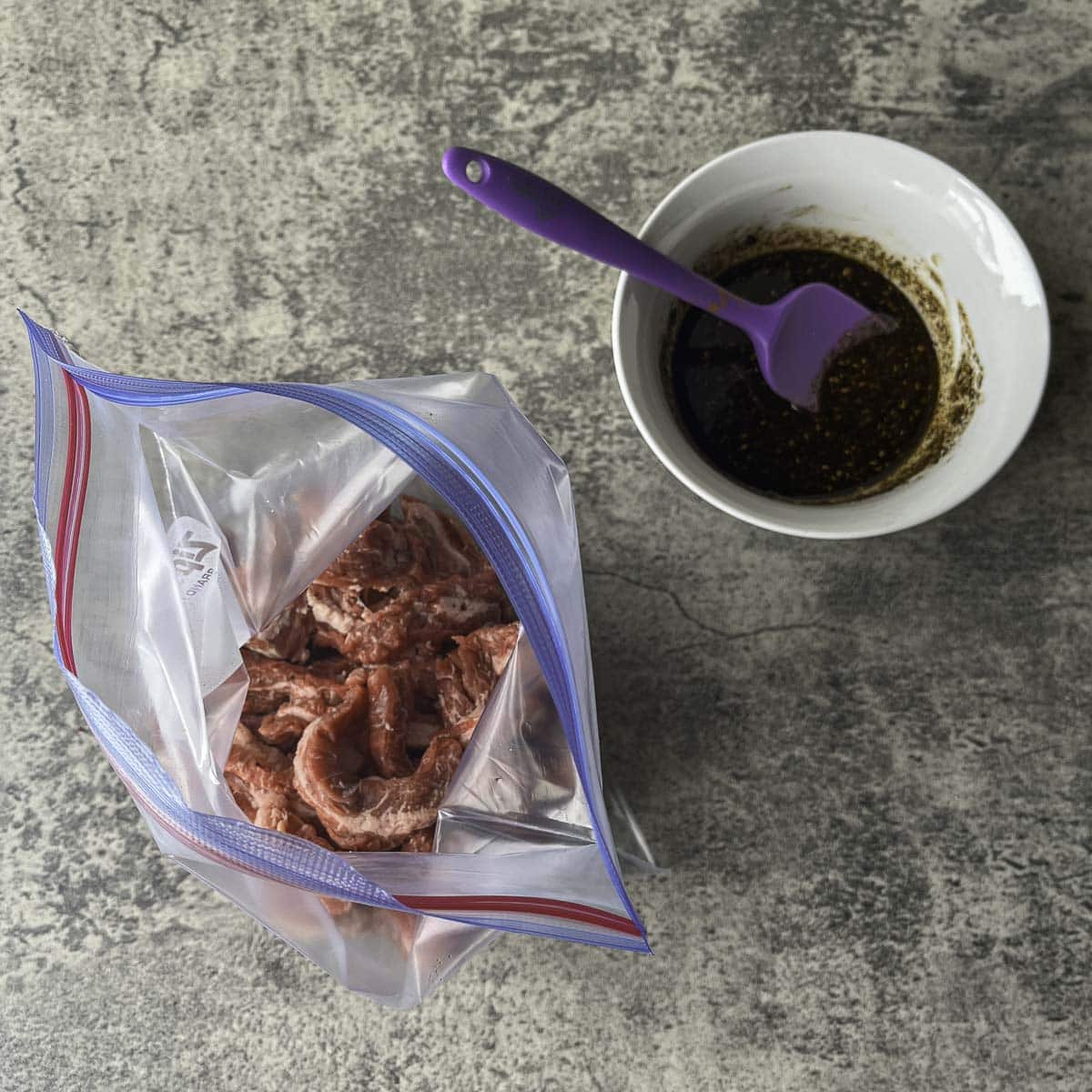 sliced beef in a plastic bag with sharawma marinade next to it