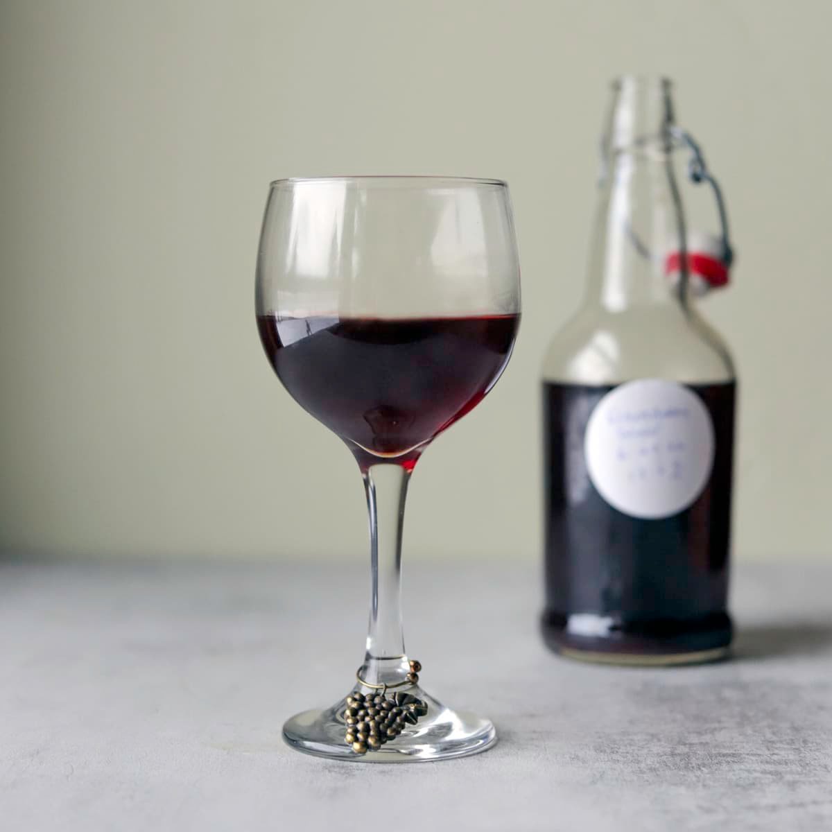 elderberry wine in a glass with more in a bottle behind it
