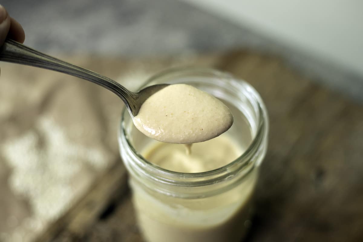 tahini sauce being spooned out of a jar