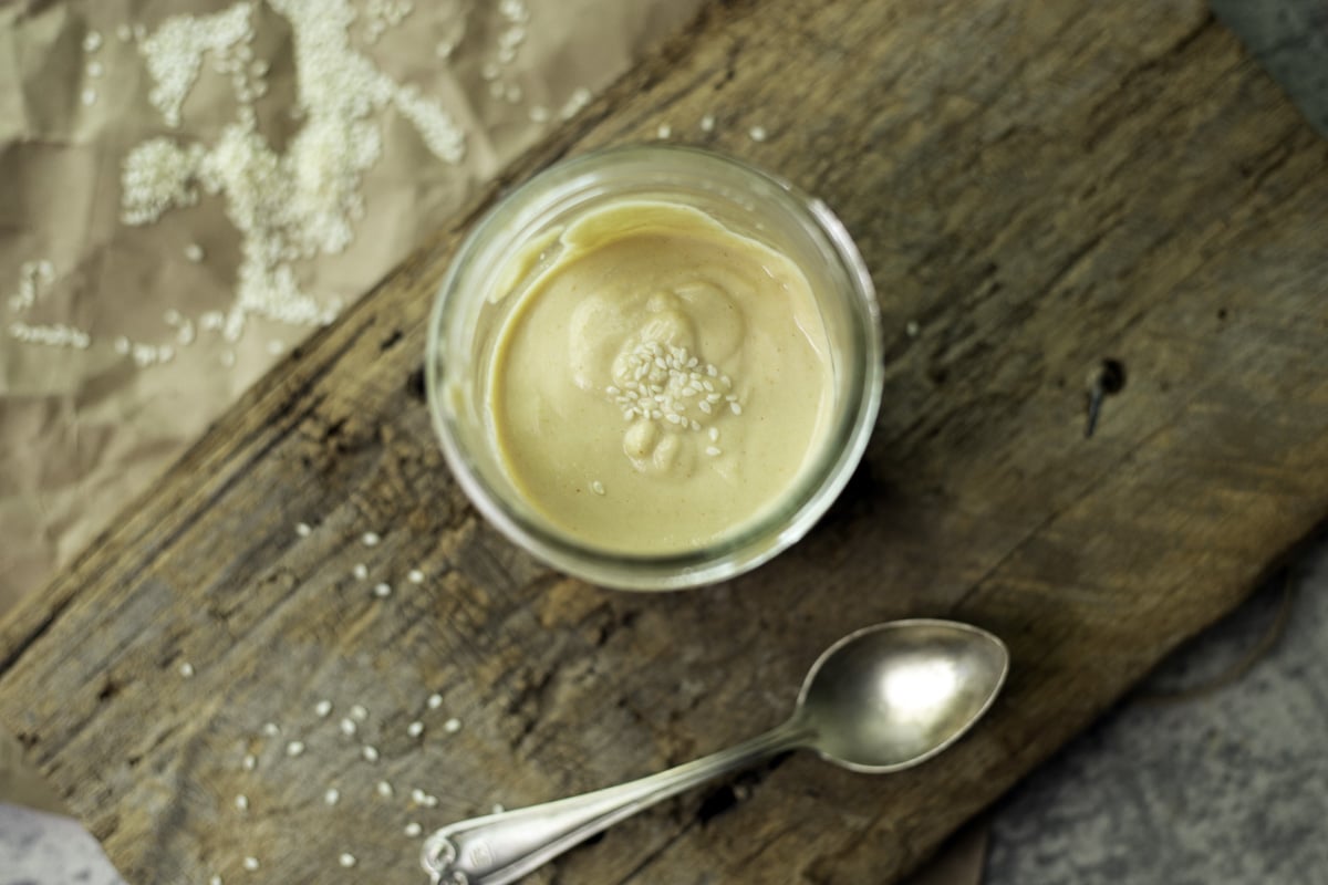 tahini sauce in a jar with a spoon under it