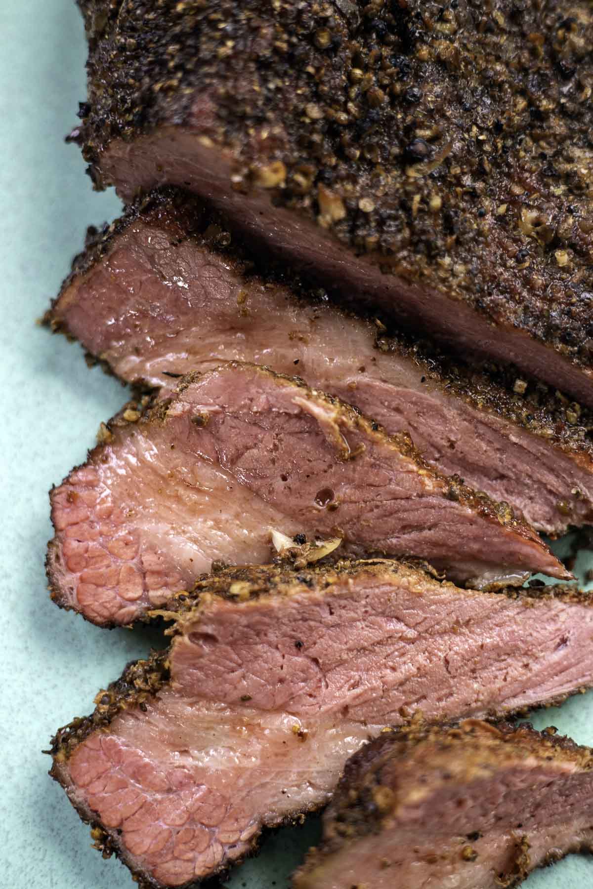 smoked corned beef sliced on a blue cutting board