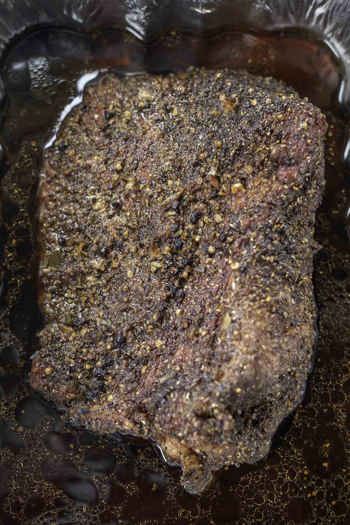 smoked corned beef brisket in a pan of liquid