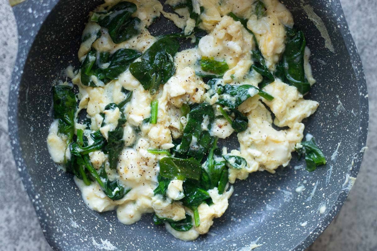 scrambled eggs and spinach in a pan