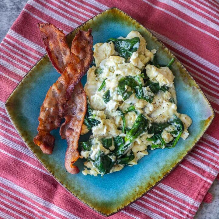 scrambled eggs and bacon on a blue plate
