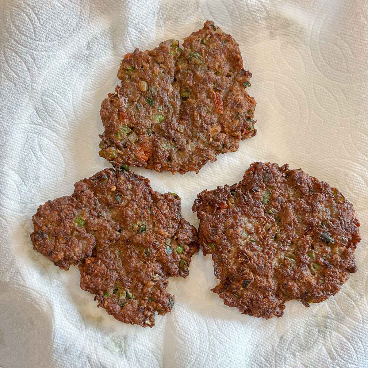 3 meat patties draining on paper towels