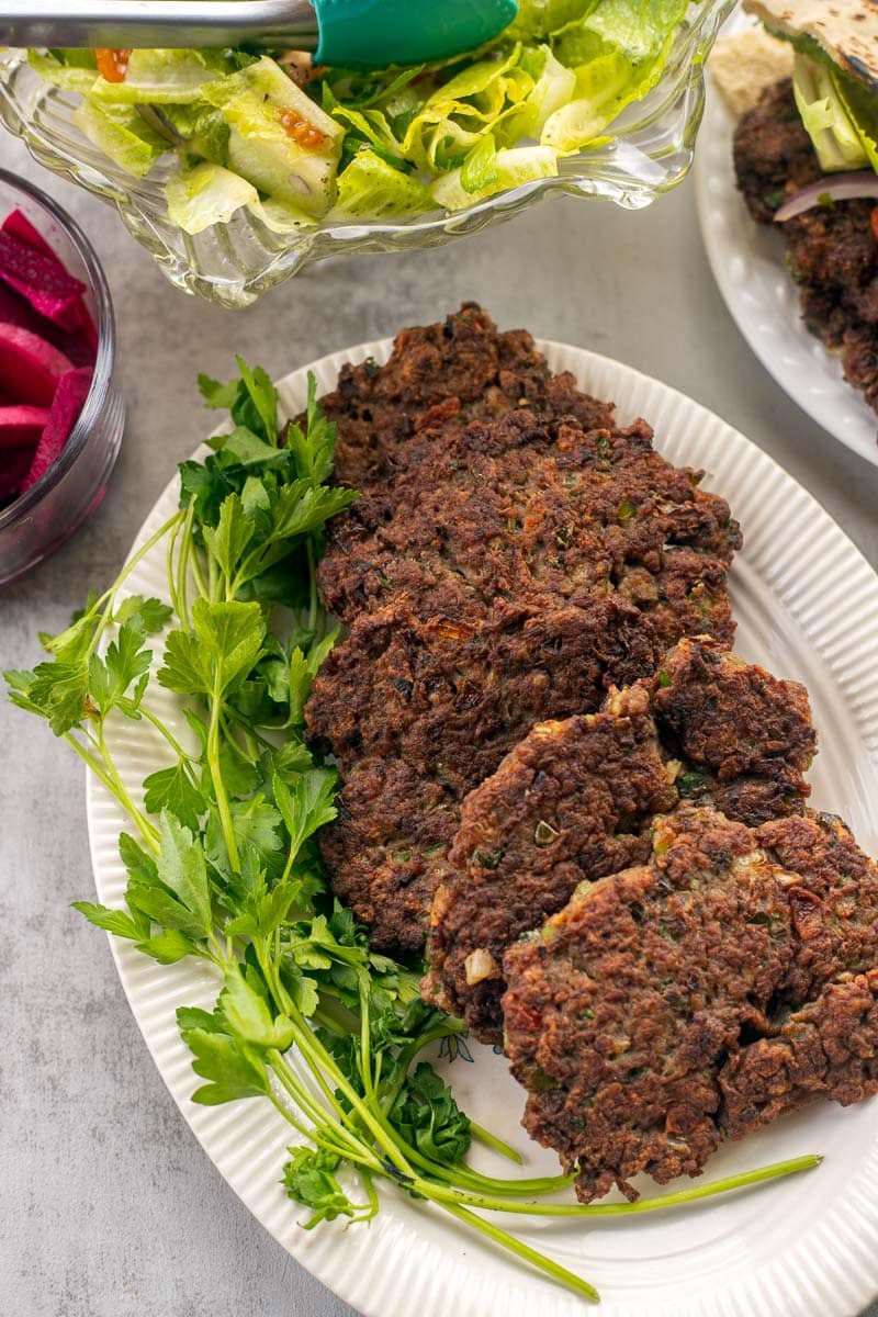 arook meat patties on a white plate with sides