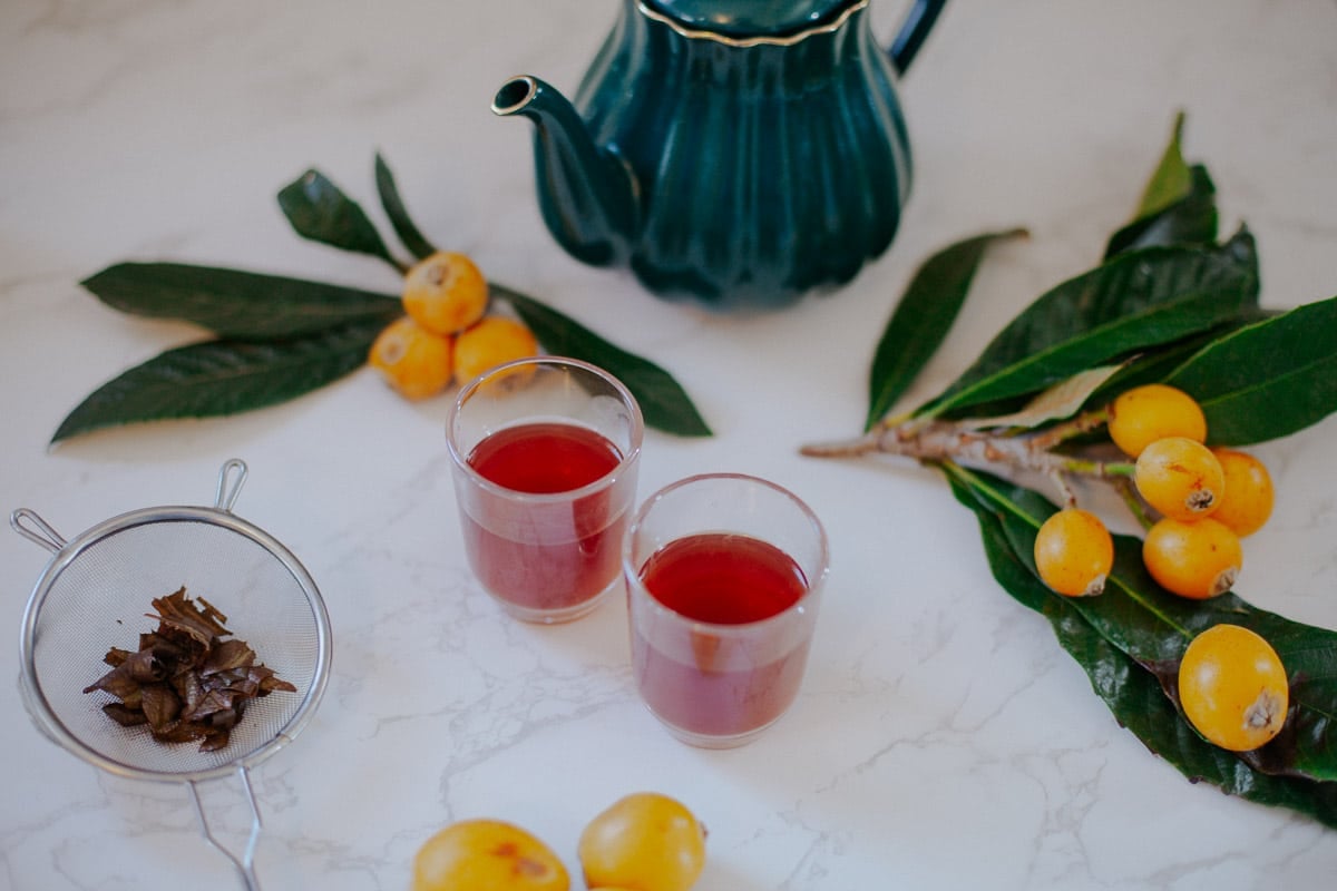 loquat tea with loquats around it and a green tea pot