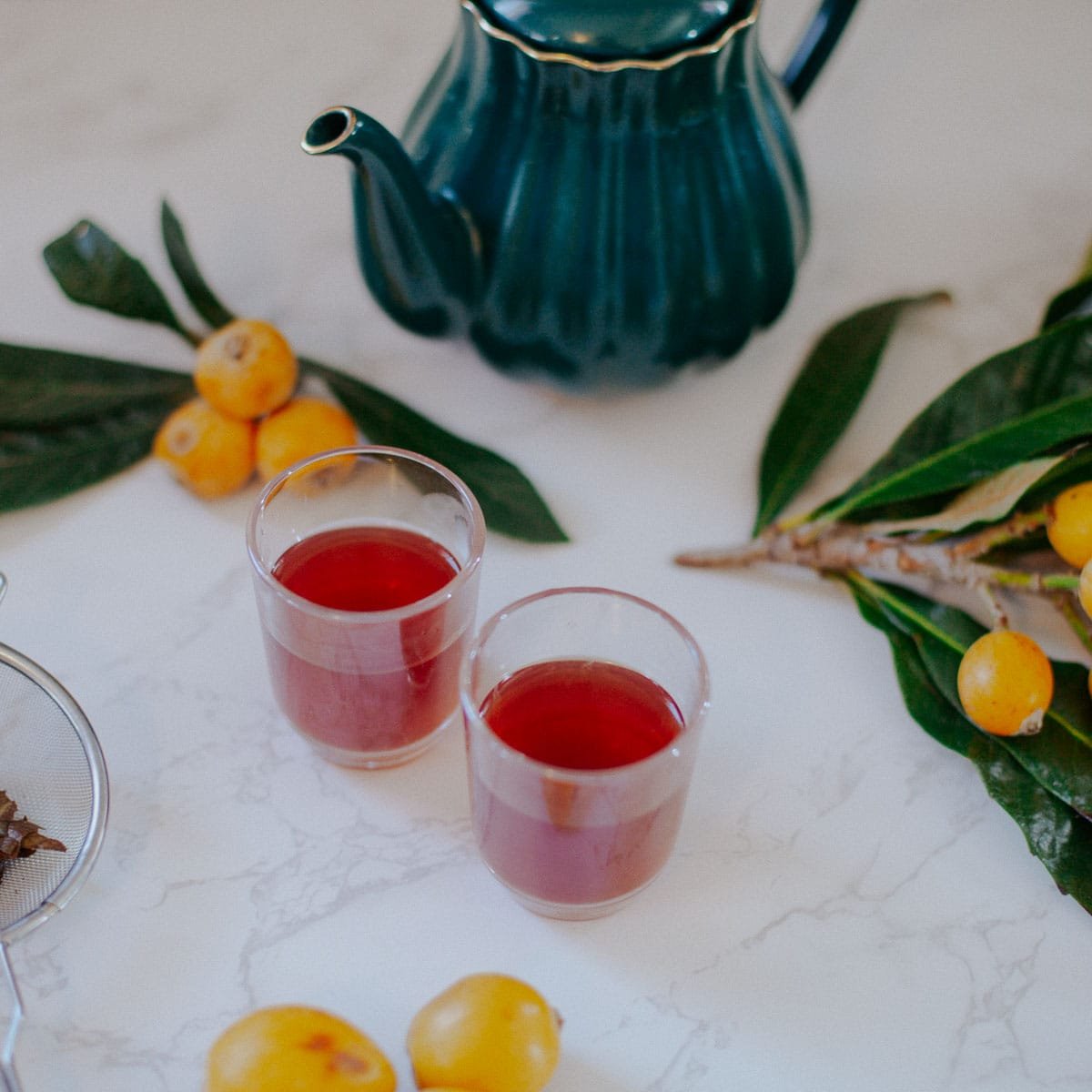 loquat tea with tea pot, loquats and leaves around it