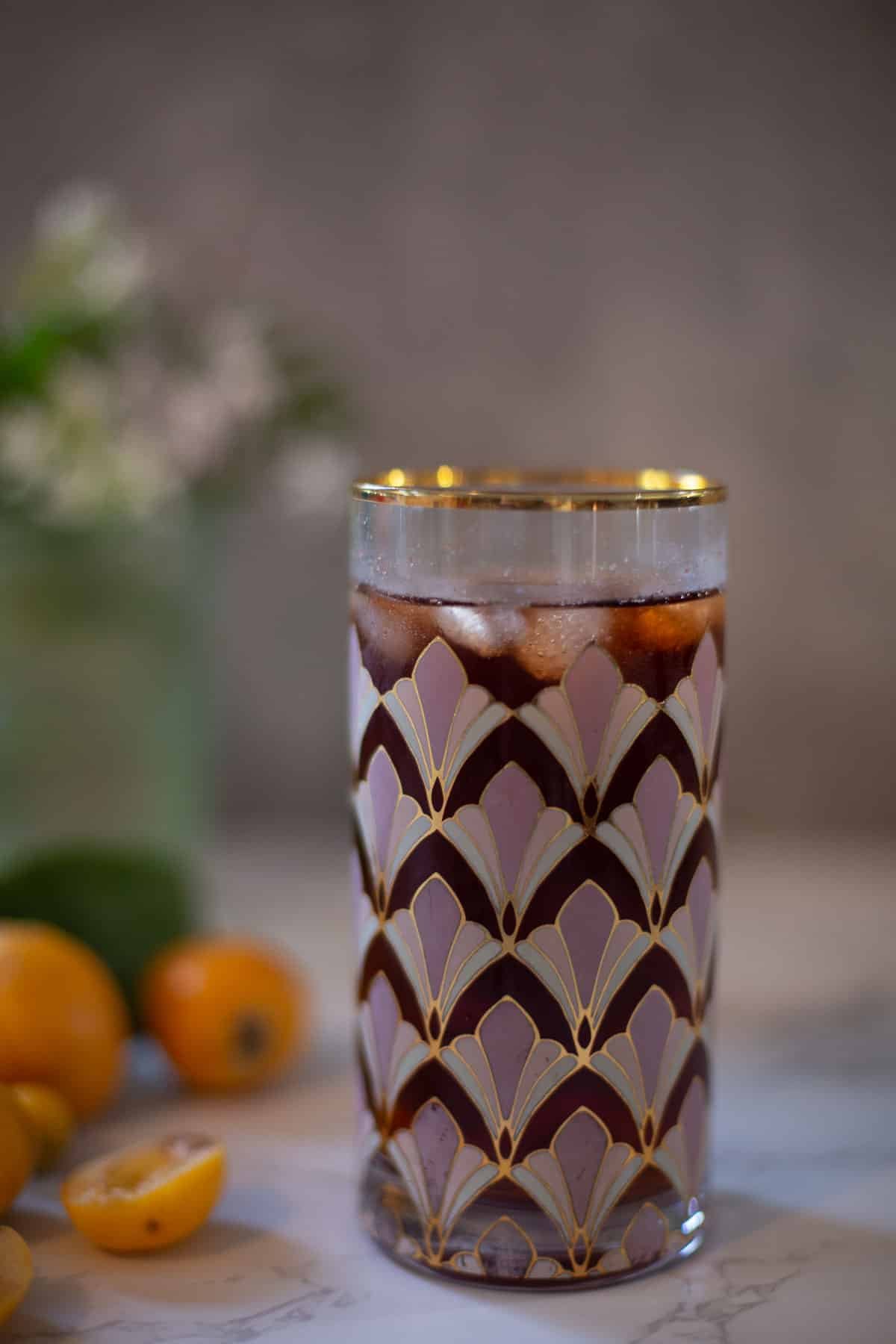 loquat tea in a glass with loquats in the background