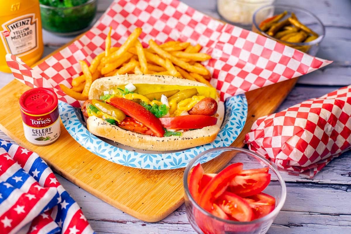 chicago dog on a blue paper plate with fries and fixings