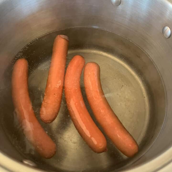4 hot dogs being boiled