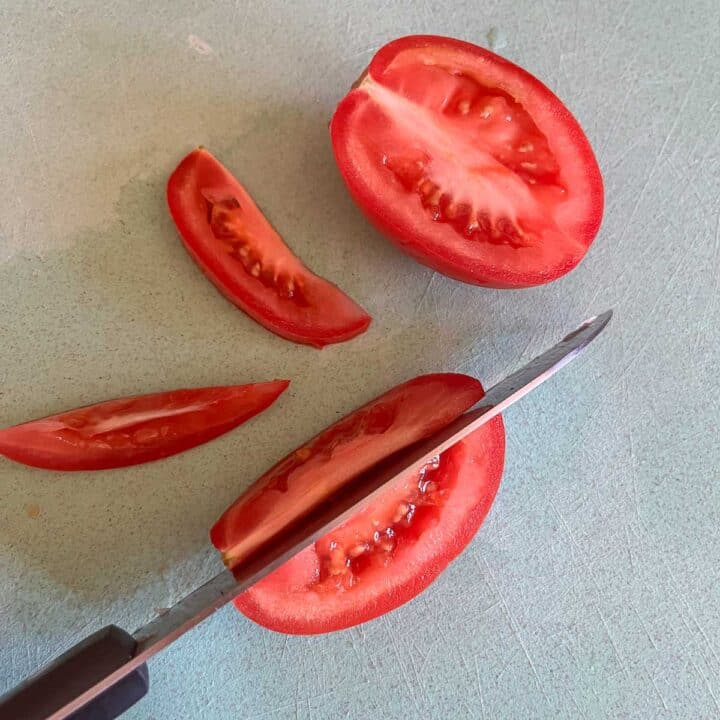 sliced tomato on a blue cutting board