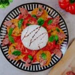 salad on plate before burrata is cut, drizzled with balsamic glaze