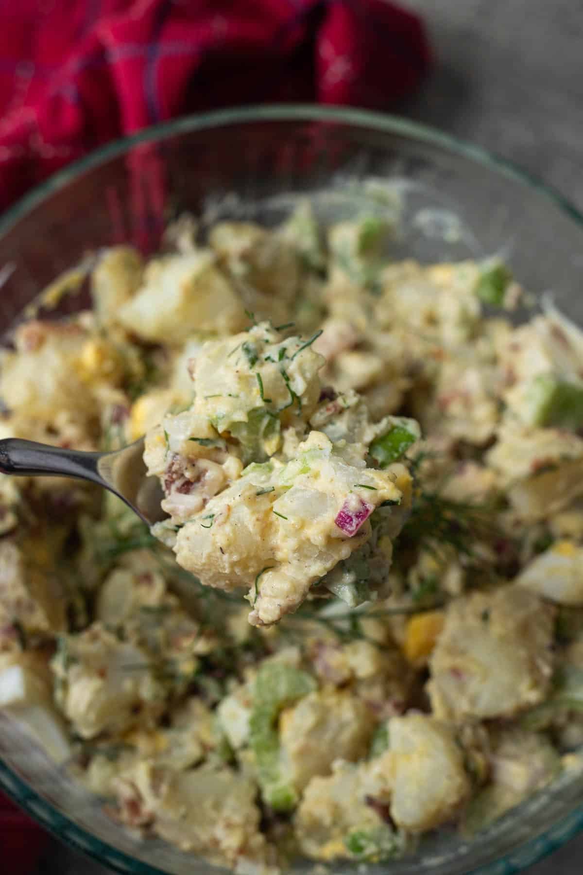spooning dill potato s salad out of bowl