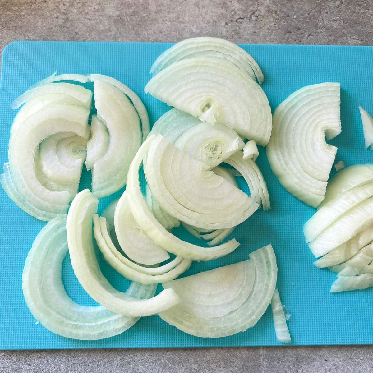thinly sliced onions on cutting board