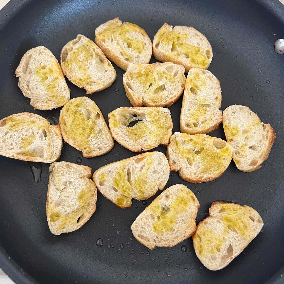 baguette slices drizzled in oil in pan