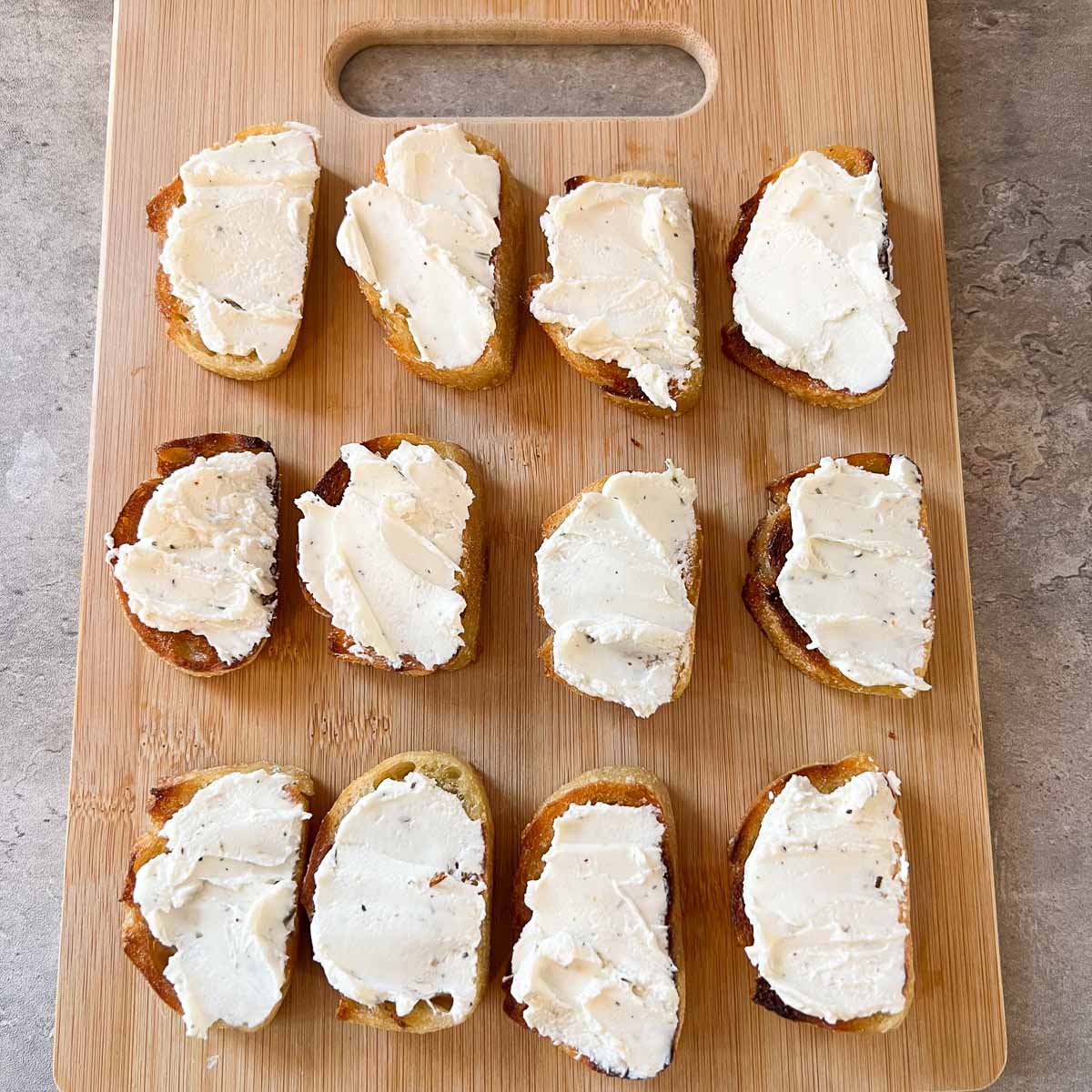 crostini with goat cheese on top on a cutting board