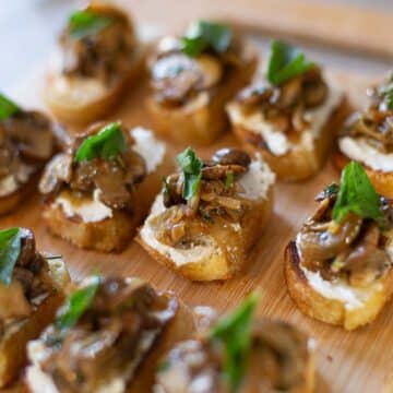 mushroom bruschetta with goat cheese and parsley to garnish, all on cutting board