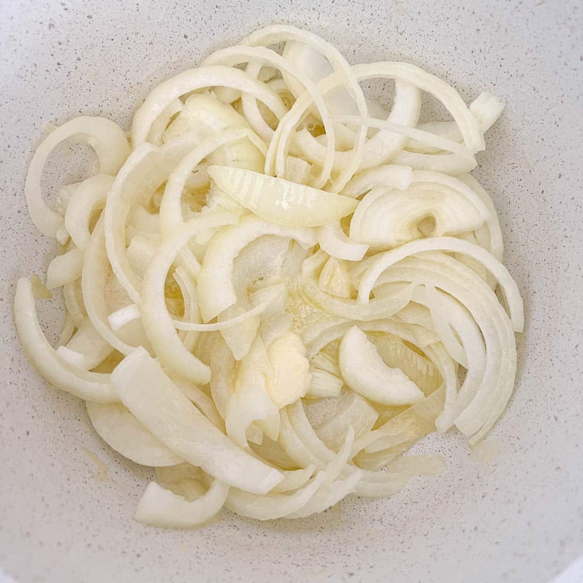 thinly sliced onions in pot with butter