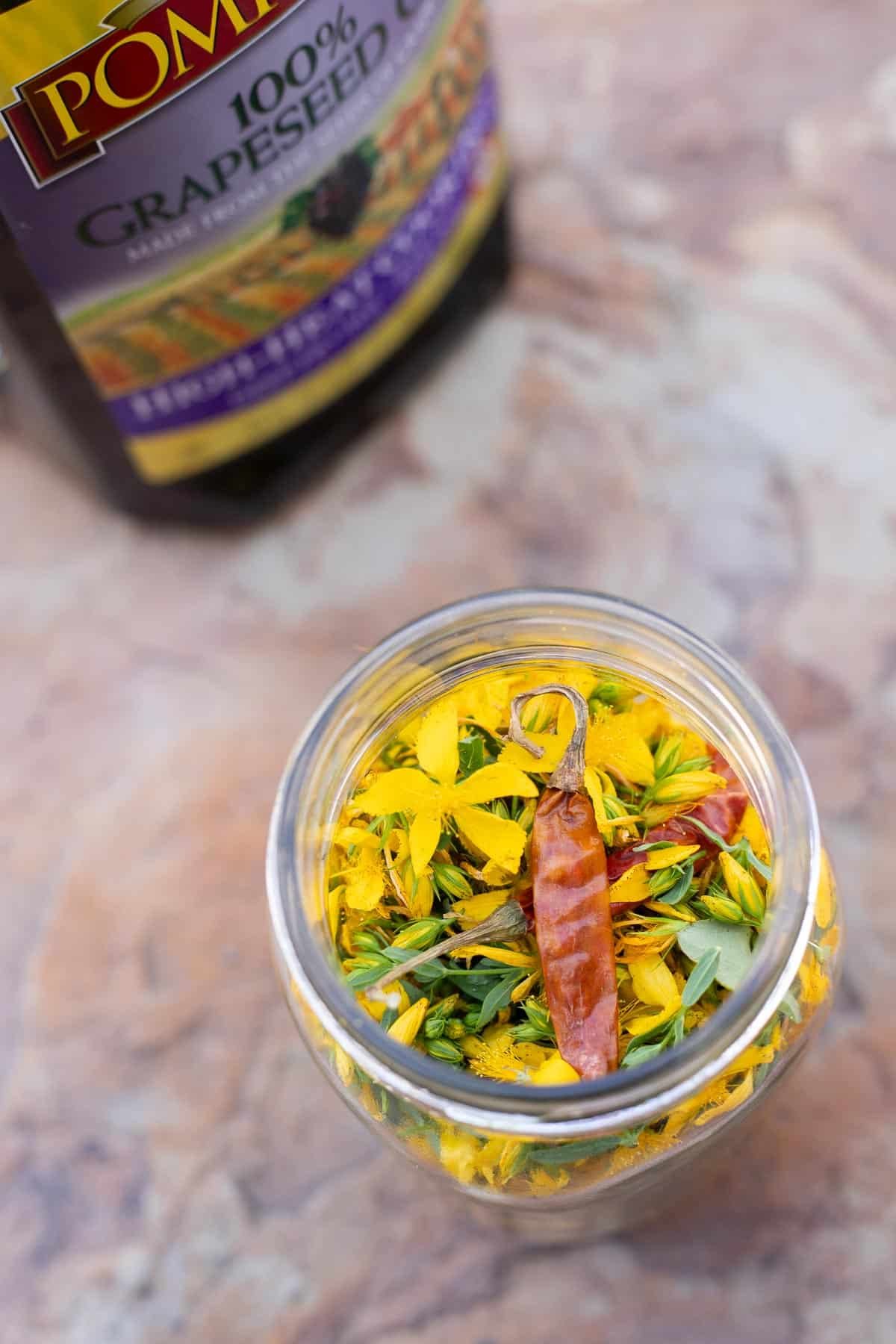 st johns wort flowers in a jar topped with a few cayenne peppers