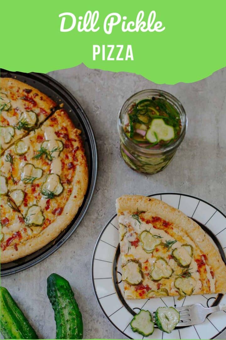 dill pickle pizza slice on plate beside remaining pizza, jar of pickles, cucumbers