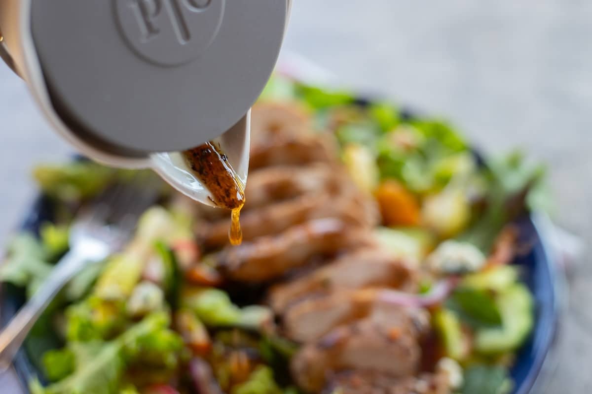 pouring huckleberry vinaigrette on a salad