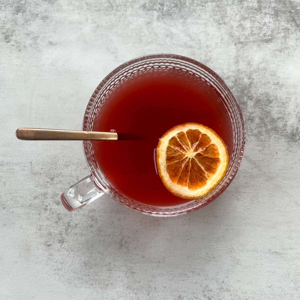 elderberry tea with orange slice and brass spoon