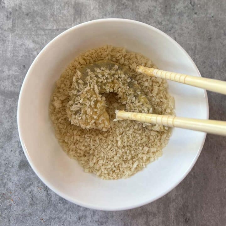 shrimp being dipped in panko crumbs with chopsticks