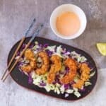 panko shrimp on bed of cabbage with chopsticks and spicy mayo on side