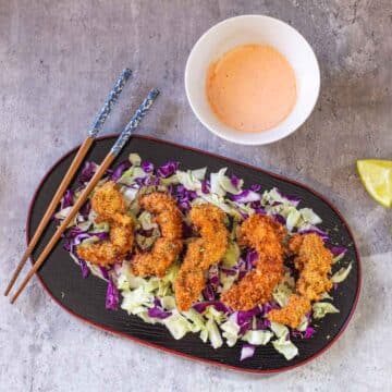 panko shrimp on bed of cabbage with chopsticks and spicy mayo on side